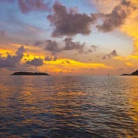 dramatic sunset on holiday in phuket across the sea with cloud formations and outlying islands