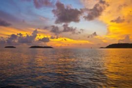 dramatic sunset on holiday in phuket across the sea with cloud formations and outlying islands